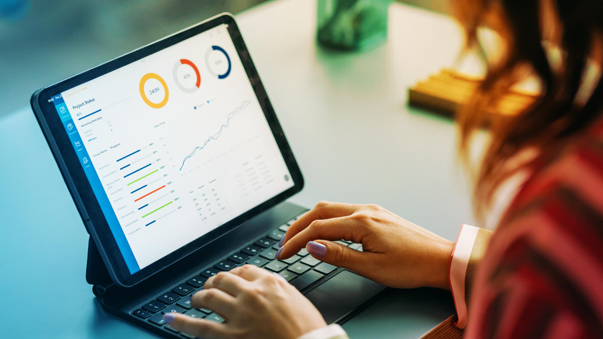Woman typing on laptop with charts on screen